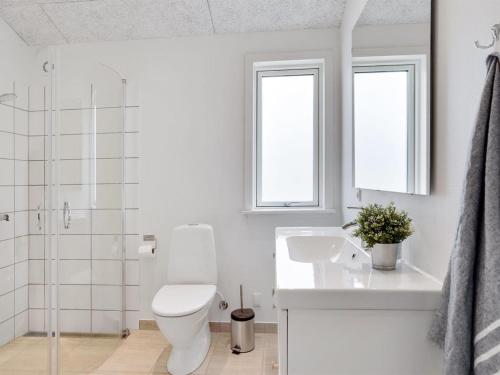 a white bathroom with a toilet and a sink at Holiday Home Raakel - 950m from the sea by Interhome in Torsted