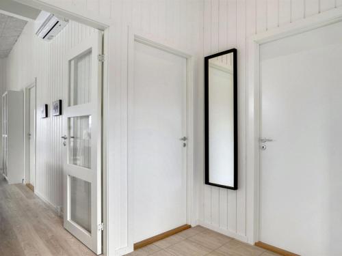 a hallway with two white doors and a mirror at Holiday Home Raakel - 950m from the sea by Interhome in Torsted