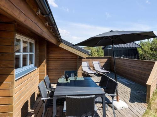 una terraza de madera con mesa y sombrilla en Holiday Home Eggerich - 900m from the sea in NW Jutland by Interhome, en Torsted