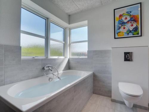 ein Bad mit einer Badewanne, einem WC und Fenstern in der Unterkunft Holiday Home Ingwio - 1-5km from the sea in NW Jutland by Interhome in Torsted
