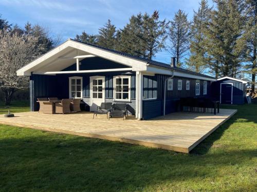 ein blau-weißes Haus mit einer Holzterrasse in der Unterkunft Holiday Home Nanja - 759m from the sea in NW Jutland by Interhome in Løkken