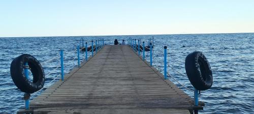 a pier in the water with a person standing on it at Happy Life Village Dahab in Dahab