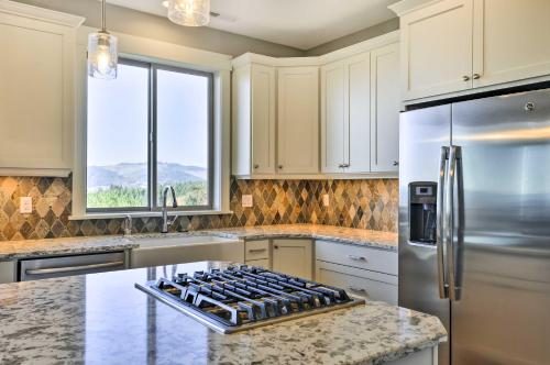a kitchen with white cabinets and a stainless steel refrigerator at Chic Willamette Valley Home with Deck and Vineyard! in Gaston