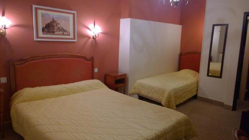 a hotel room with two beds and a mirror at Hôtel Saint - Pierre in Villedieu-les-Poëles