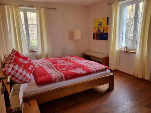 een slaapkamer met een bed met rode dekens en kussens bij Bergwirtschaft Tiefmatt in Holderbank