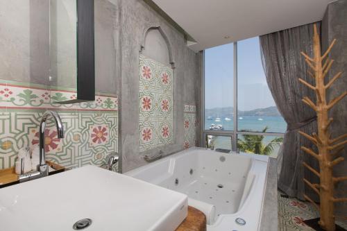 ein Badezimmer mit Badewanne und großem Fenster in der Unterkunft Patong Signature Boutique Hotel in Patong Beach