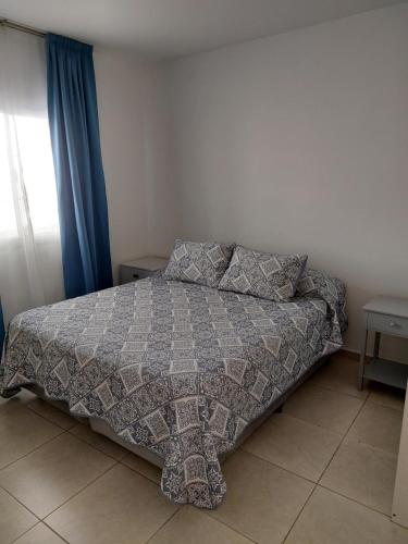ein Schlafzimmer mit einem Bett mit einer Decke und Kissen in der Unterkunft Departamento centrico in San Luis