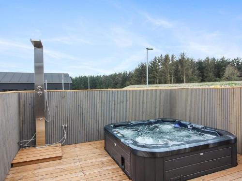 een hot tub op een terras met een hek bij Holiday Home Haddingus - 950m from the sea in NW Jutland by Interhome in Løkken