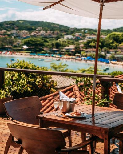 a wooden table with wine glasses and an umbrella at Jubarte Hotel by Insólito in Búzios