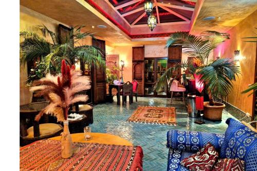 a living room with palm trees and a table at Riad Agraba, 1001 nights in Lomm