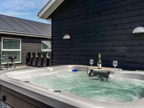 a hot tub with two glasses of wine in it at Holiday Home Dwerg - 1-5km from the sea in NW Jutland by Interhome in Løkken