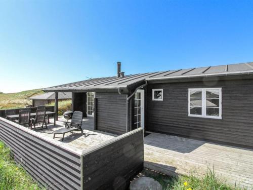 una casa con una terraza con sillas. en Holiday Home Adelita - 100m from the sea in NW Jutland by Interhome, en Løkken
