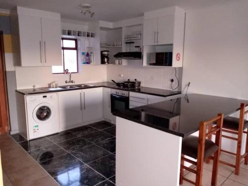 een keuken met witte kasten, een wastafel en een vaatwasser bij Gabby's apartment in Kaapstad