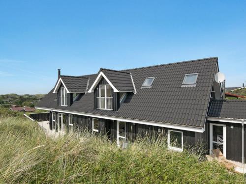 a house with a black roof on the beach at Holiday Home Skamhals - 700m from the sea in NW Jutland by Interhome in Blokhus