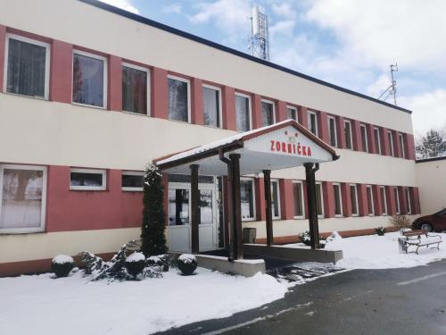 a building with a sign for a inn in the snow at Penzion Zornicka in Bardejovské Kúpele
