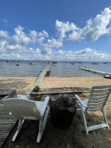 a couple of chairs sitting on a beach next to the water at CLEARVIEW LIMIT 6 villa in North Sebago