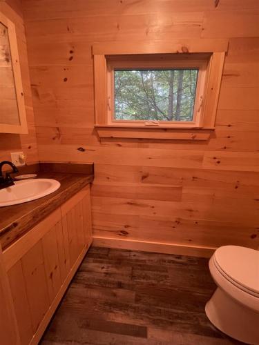a bathroom with a toilet and a sink and a window at MAINE PINES LMIT 8 home in Denmark