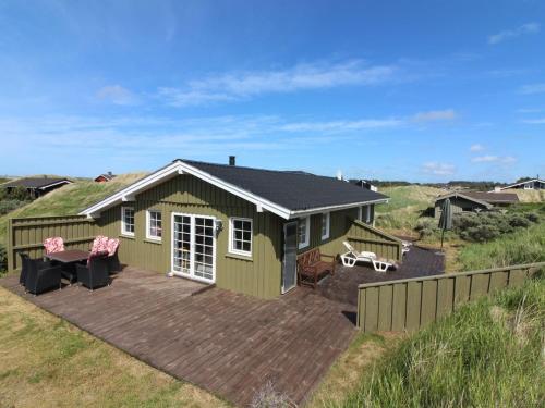 een groen huis met een terras in een veld bij Holiday Home Arita - 250m from the sea in NW Jutland by Interhome in Saltum