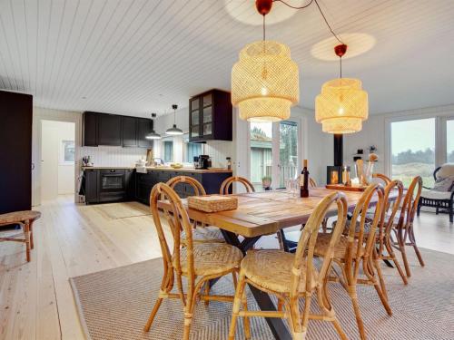 cocina y comedor con mesa de madera y sillas en Holiday Home Ayelen - 600m from the sea in NW Jutland by Interhome, en Saltum