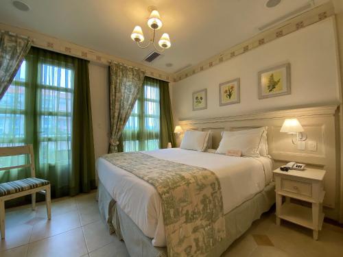 a bedroom with a large white bed and windows at Il Campanário Jurerê Internacional - Studio in Florianópolis