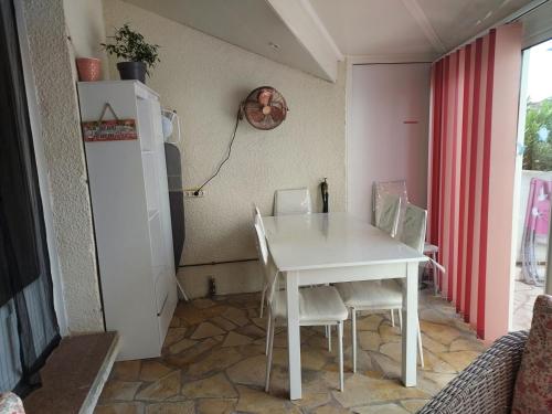 une petite cuisine avec une table et des chaises blanches dans l'établissement Maison coup de coeur, à Marseillan