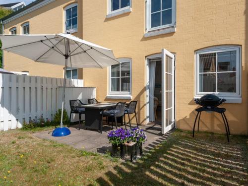 un patio con mesa, sombrilla y parrilla en Apartment Cornel - 400m from the sea in NW Jutland by Interhome, en Hjørring