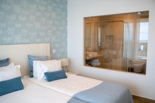 Schlafzimmer mit einem Bett mit einem Spiegel und einem Badezimmer in der Unterkunft Sunrise Villa in Sagres