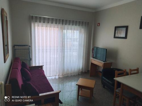 a living room with a couch and a table and a television at Casa Alvor - a criar Memórias in Alvor