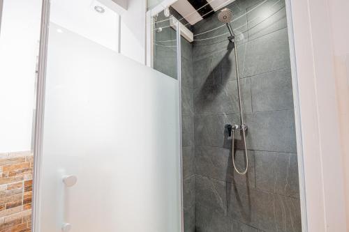 La salle de bains est pourvue d'une douche avec une porte en verre. dans l'établissement Apartamento 1 en la muralla romana junto a la Catedral, à Tarragone