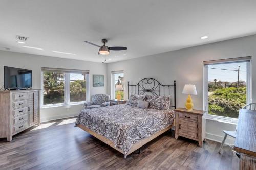 a bedroom with a bed and a tv and windows at Salt Therapy North and South in Saint Augustine