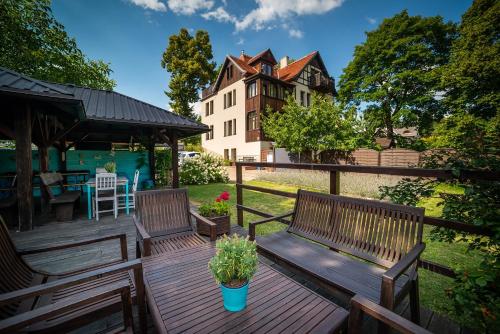 zwei Bänke auf einem Deck mit einem Haus im Hintergrund in der Unterkunft Willa Kwiaty Polskie in Jedlina-Zdrój