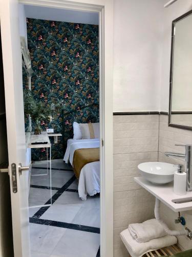 a bathroom with a bed and a sink and a mirror at Apartamentos Makao Puerta del Olivillo in Jerez de la Frontera