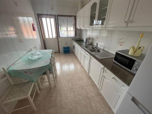 a white kitchen with a table and a sink at Blue Tex in Vila Chã