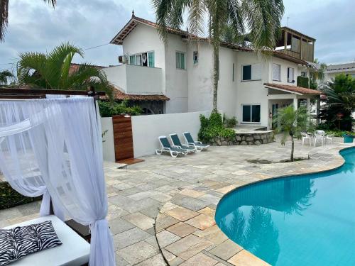 a backyard with a pool and a house at Pousada Tortugas in Guarujá