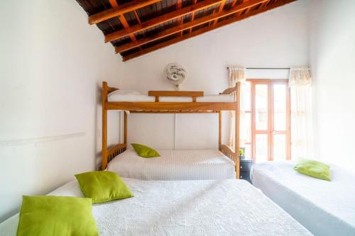 two beds in a room with white walls and green pillows at Hotel Cabañas Villa Roca, Rodadero in Santa Marta