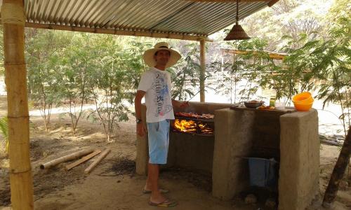 Ein Mann mit Hut steht neben einem Kamin in der Unterkunft Camping Matufa Mancora in Canoas De Punta Sal