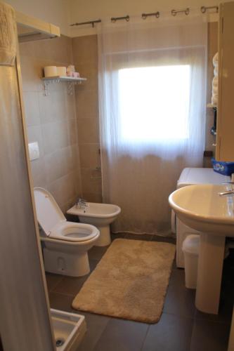 łazienka z toaletą, umywalką i oknem w obiekcie CASA VACANZE DA RIKI w mieście Peschiera del Garda
