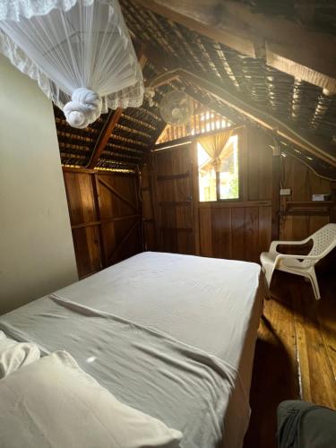 a bedroom with a white bed and a chair at Zutalu - Playa Sur in Puerto López