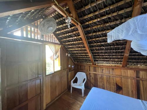 a room with a white chair and a ceiling at Zutalu - Playa Sur in Puerto López