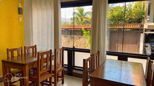 d'une salle à manger avec une table, des chaises et une fenêtre. dans l'établissement Pousada Vieira, à Arraial do Cabo