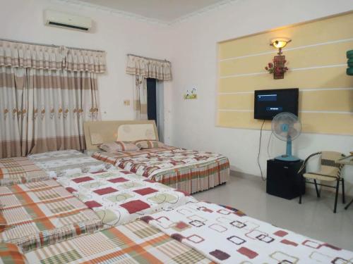 Habitación con 2 camas, ventilador y TV. en Motel Thanh Huyền en Vung Tau