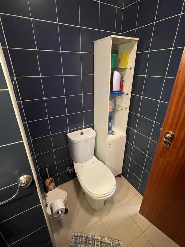 a bathroom with a white toilet and blue tiles at Farol Nascente in Lavra