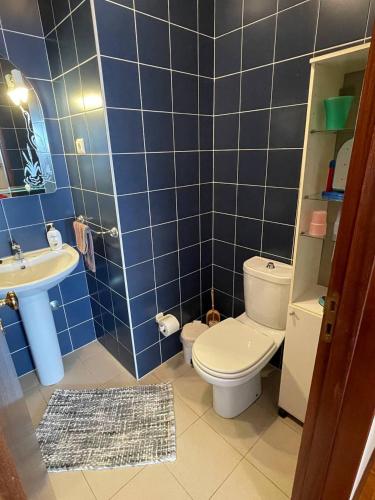 a blue tiled bathroom with a toilet and a sink at Farol Nascente in Lavra