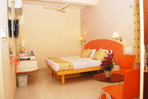 a bedroom with a bed and a table and chairs at Hotel Pandian in Chennai