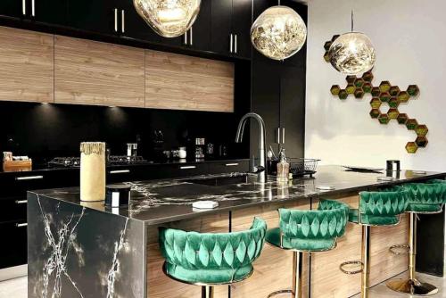 a kitchen with black cabinets and green bar stools at The Elements Luxury Home Fort Lauderdale in Fort Lauderdale