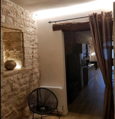 a living room with a stone wall and a chair at Appartamento Gattapone 9 in Gubbio
