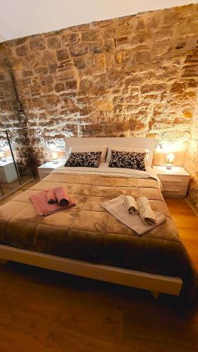 a large bed in a room with a stone wall at Appartamento Gattapone 9 in Gubbio