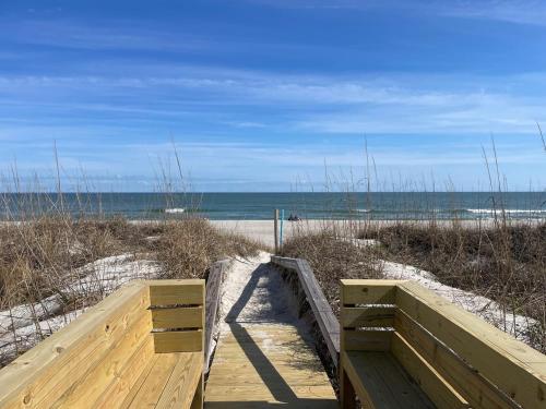 a wooden boardwalk leading to a beach with the ocean at Large Oceanfront condo in a quiet section of Carolina Beach Rentals in Carolina Beach