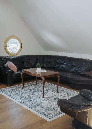 a living room with a black couch and a coffee table at Apartments Možinetova hiša in Šentjošt nad Horjulom