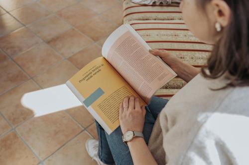 a woman sitting on the floor reading a book at Apartments Možinetova hiša in Šentjošt nad Horjulom